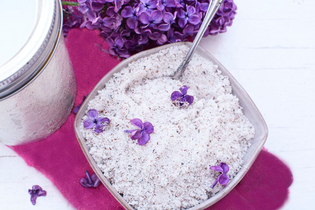 Lilac sugar in a pottery dish with a spoon coming out on the top right.