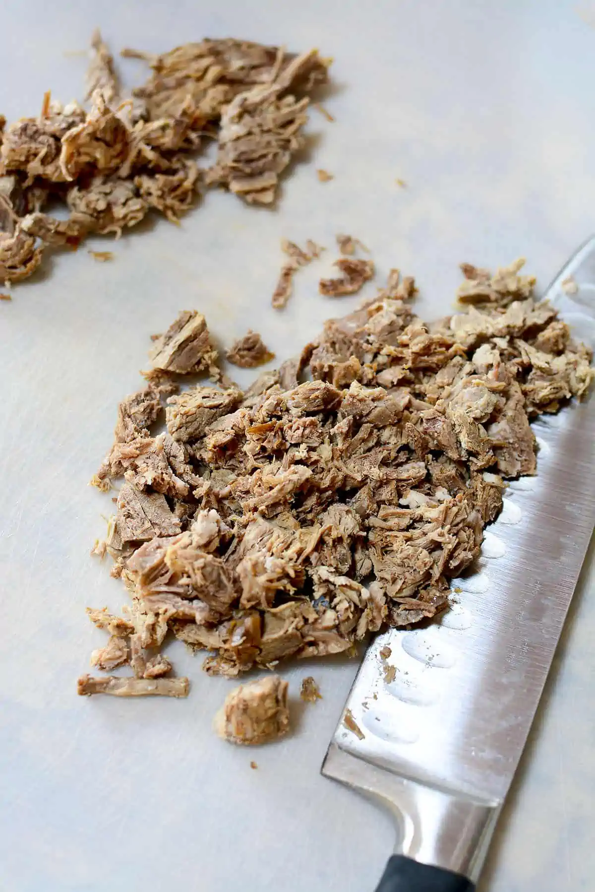 Roast beef chopped into smaller bits on a white plastic cutting board.