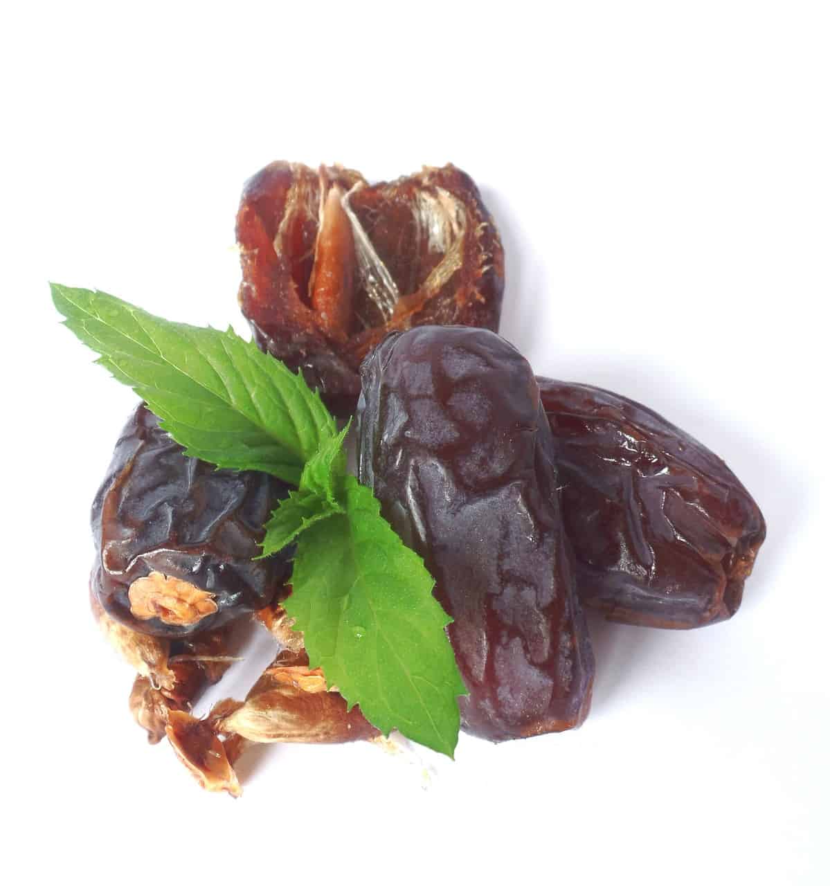 Medjool dates piled on top of eachother with a sprig of mint in the center.