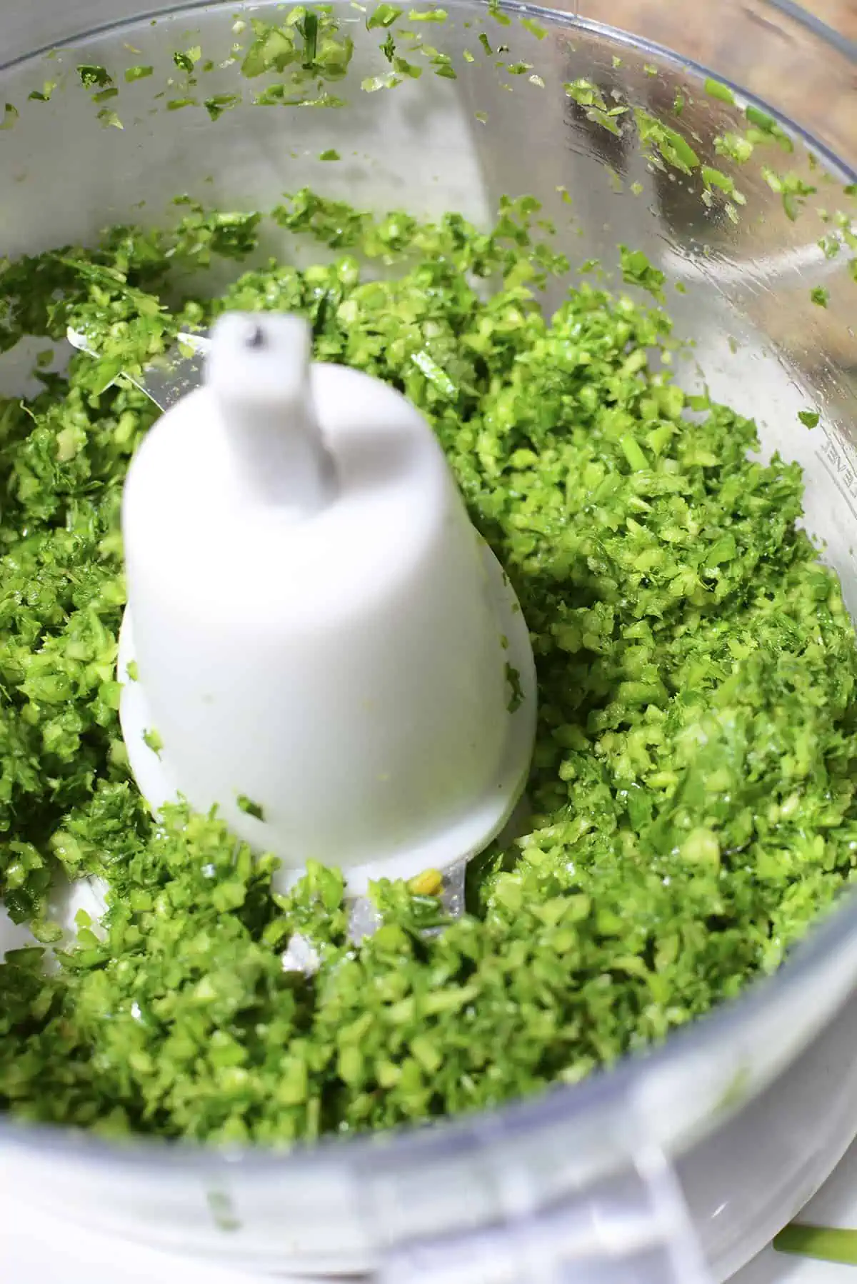 The food processor with chopped garlic scapes and herbs.