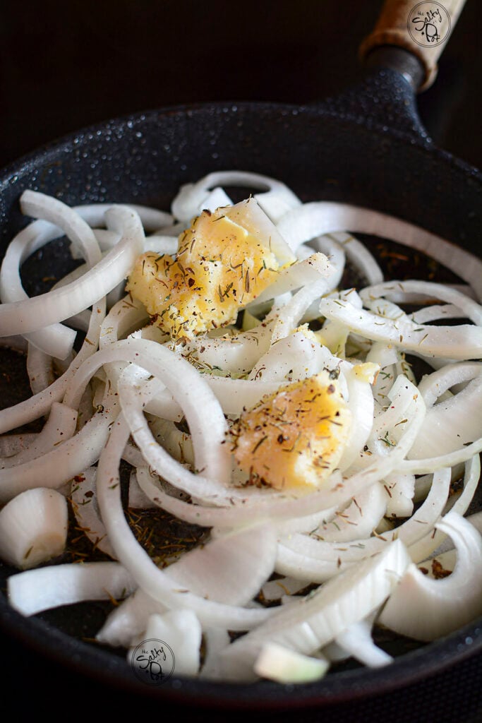 Fresh onions in a skillet with butter and dried thyme.