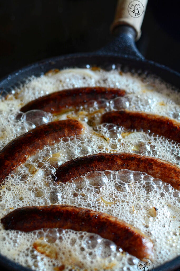 Caramelized bratwurst braising in beer.