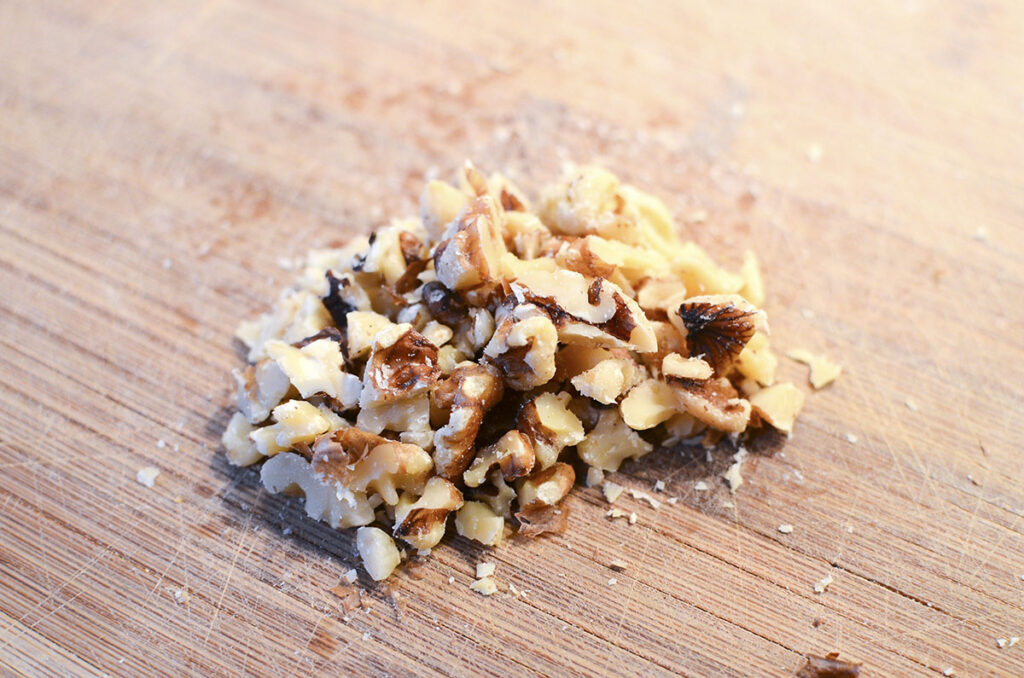 Chopped walnuts on wooden cutting board.