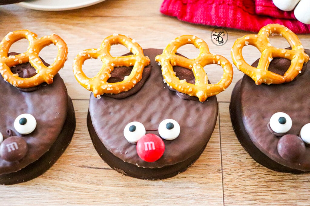 Three wagon wheel cookies are on a wood table. 