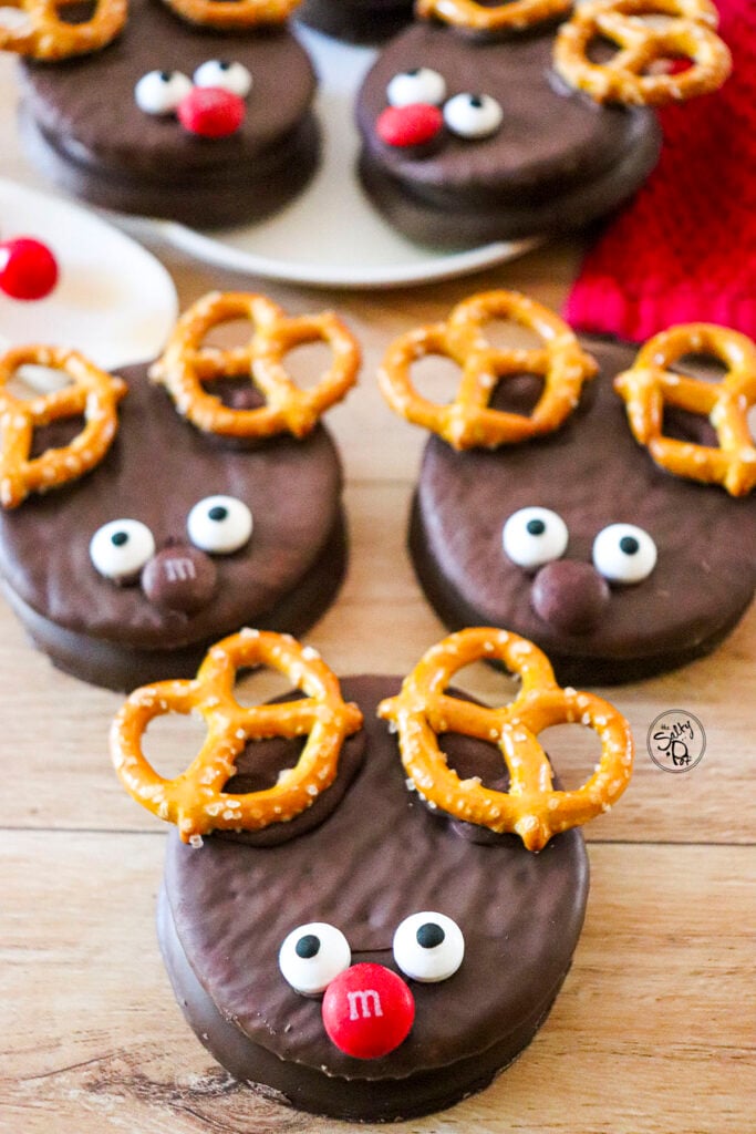 Five reindeer cookies are featured, with one focus at the bottom of the photo. There is a red napkin at the top right of the photo.