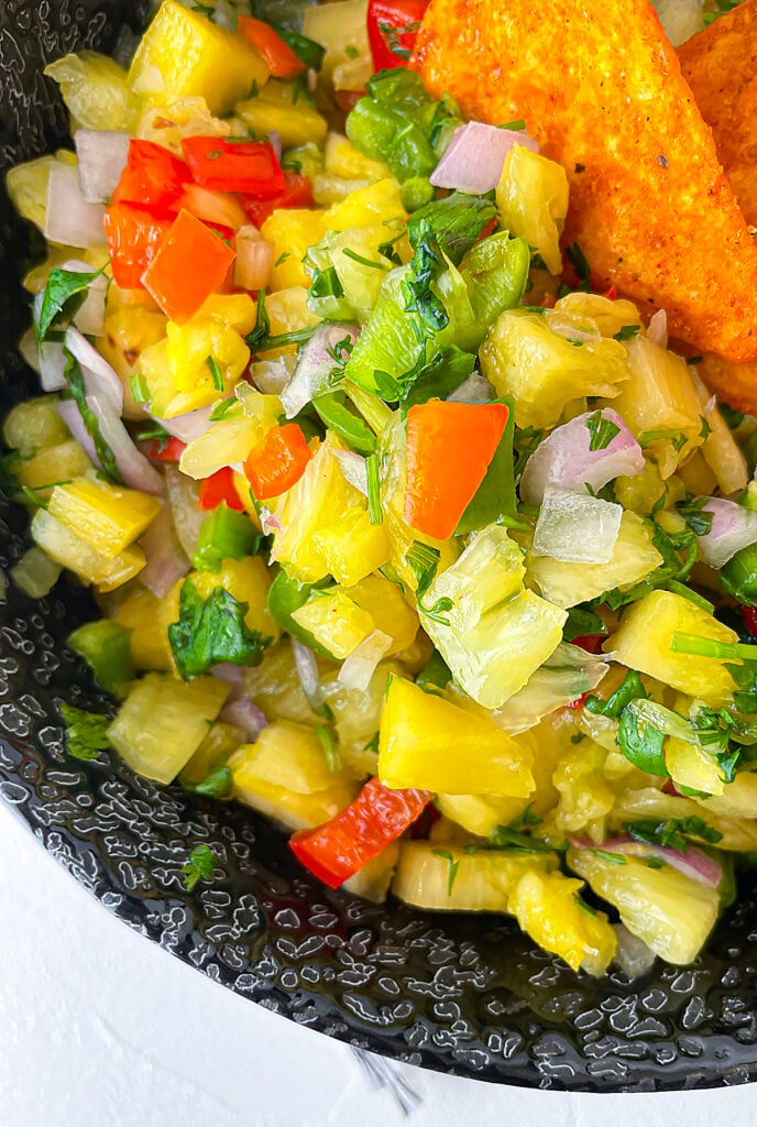 A close up photo of the pineapple habanero salsa in a black bowl.