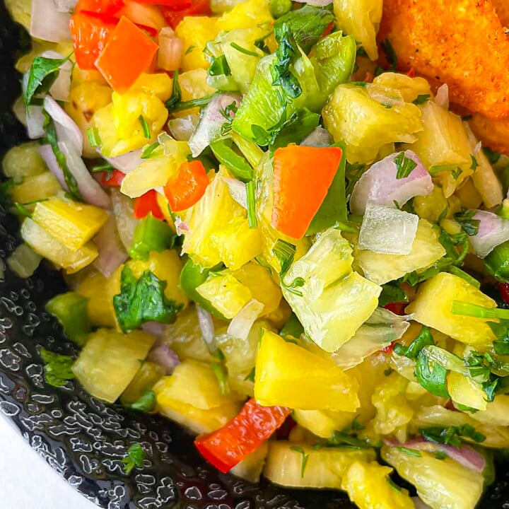 A close up photo of the pineapple habanero salsa in a black bowl.