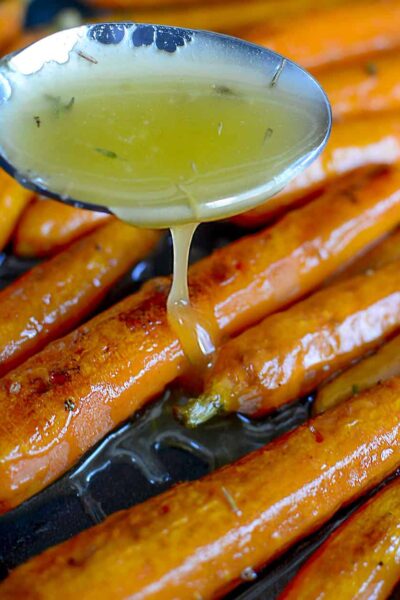 Drizzling the hot honey sauce over top the roasted carrots.