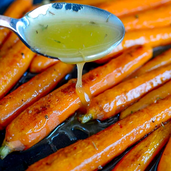 Drizzling the hot honey sauce over top the roasted carrots.