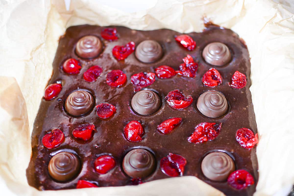 Brownie batter with added candy and maraschino cherries in parchment paper.