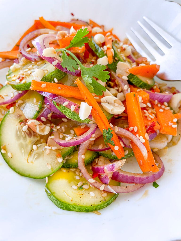 The asian carrot cucumber salad on a white plate.