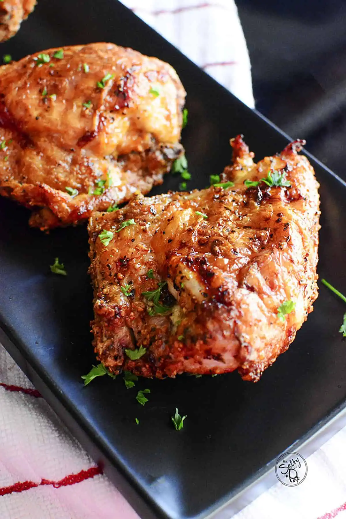 Incredibly crispy bone-in chicken breasts on a black ceramic plate.