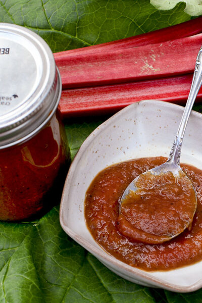 Rhubarb BBQ Sauce in a mason jar as well as in a small bowl with a spoon.