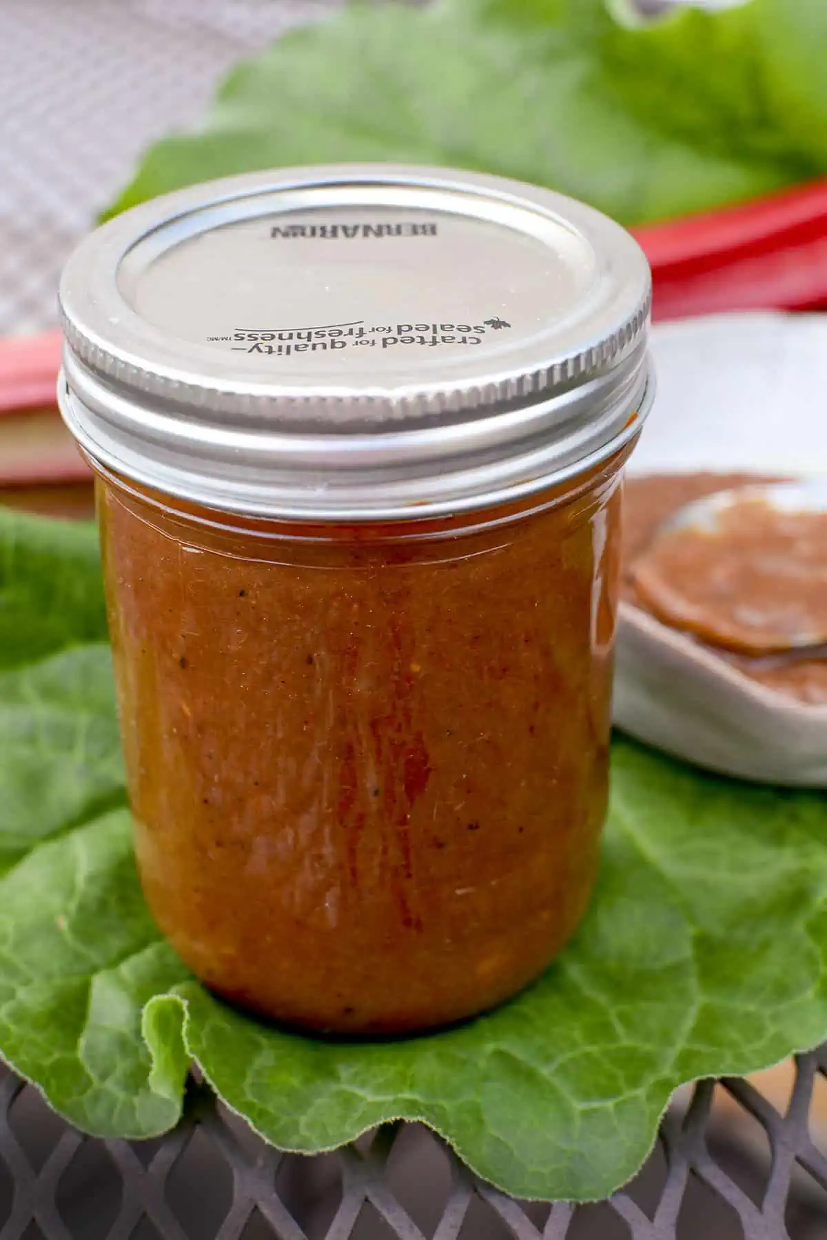 Rhubarb bbq sauce in a mason jar. The sauce is in a bowl to the upper right.