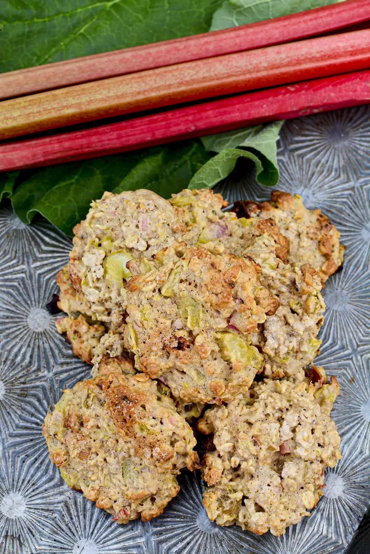 Rhubarb and oatmeal cookies piled on a vintage cookie sheet.