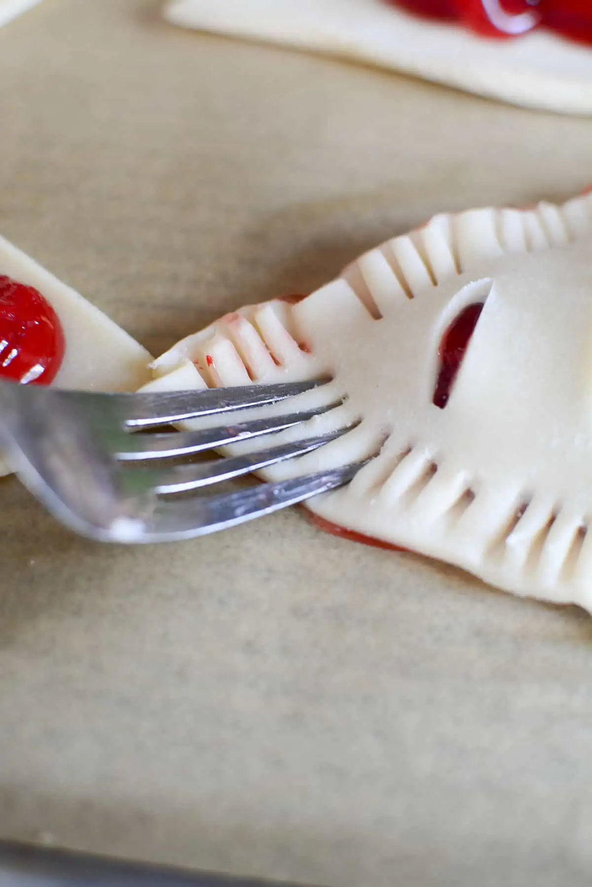 A fork pressing down on the corner of a handpie being crimped.