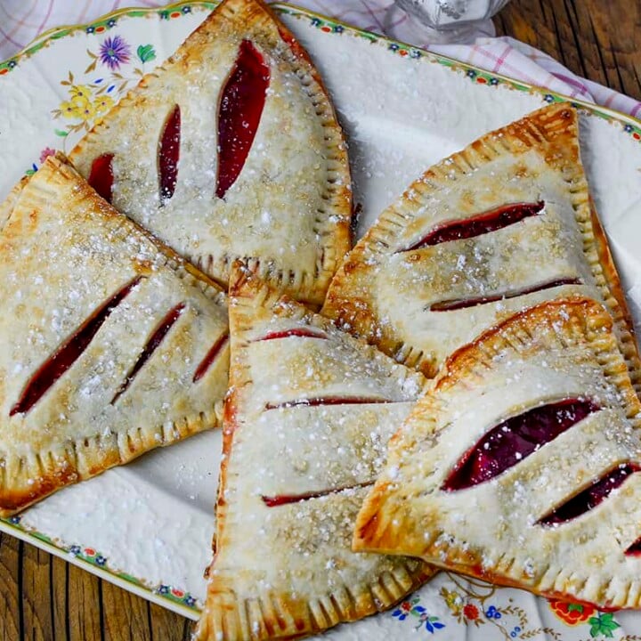Five strawberry hand pies on a decorative plate.