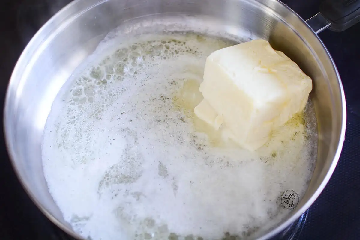 Butter is melting in a stainless steel skillet.