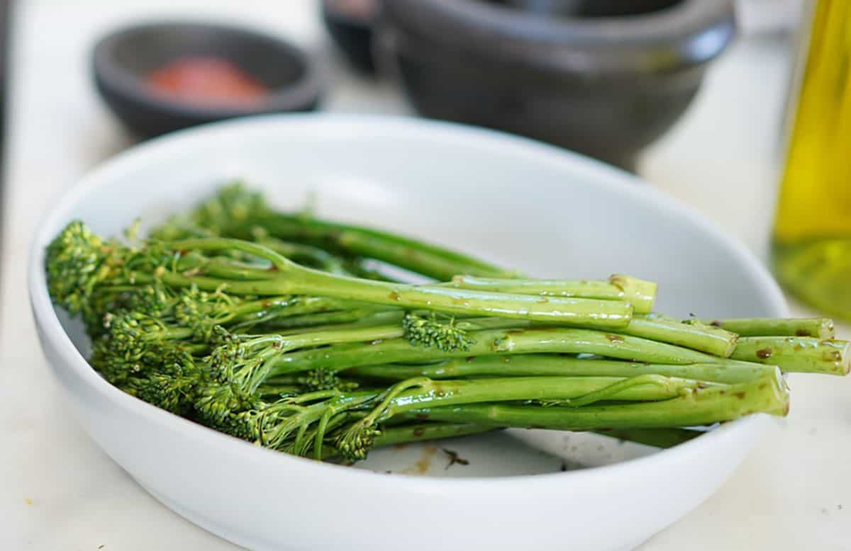 Broccolini resting in a white bowl. These will be the closest substitutes for asparagus.