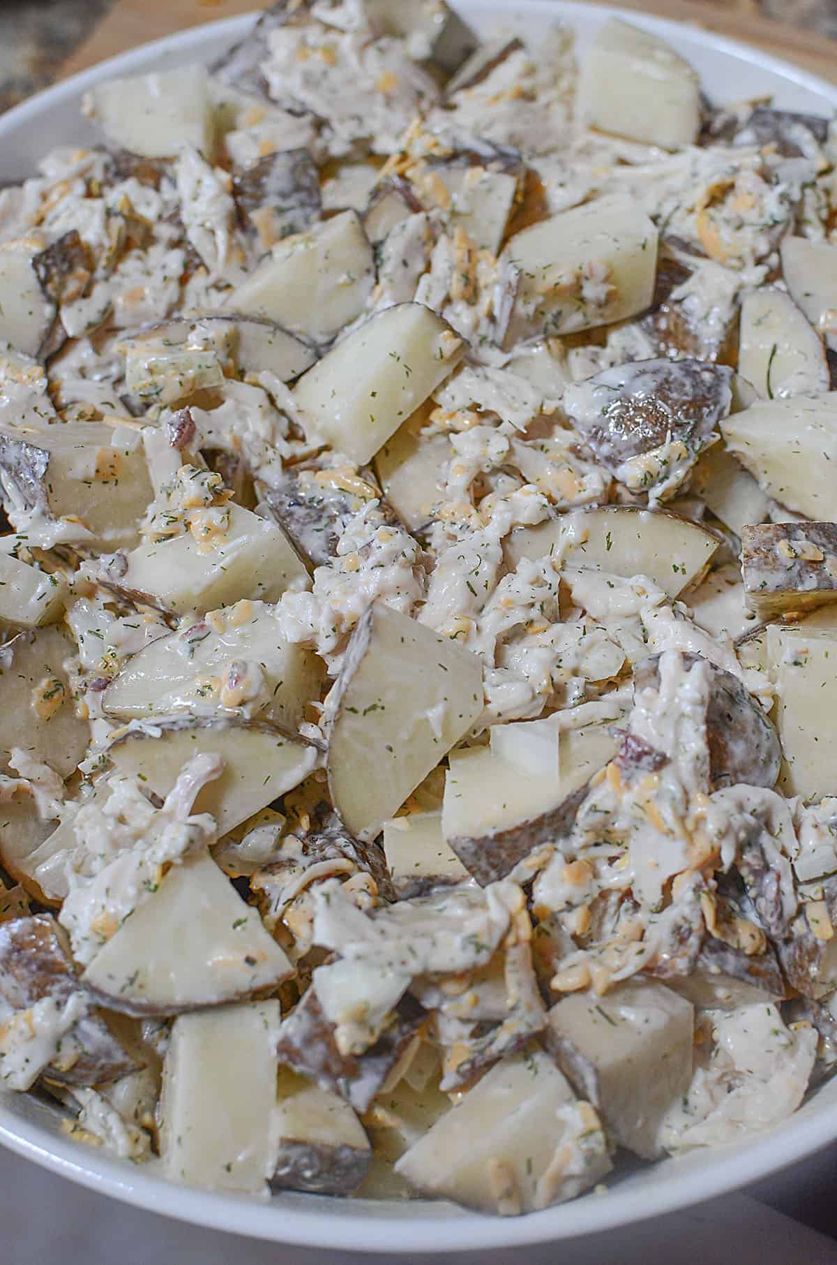 All the ingredients for the chicken potato casserole are mixed together and put into the white baking dish. 