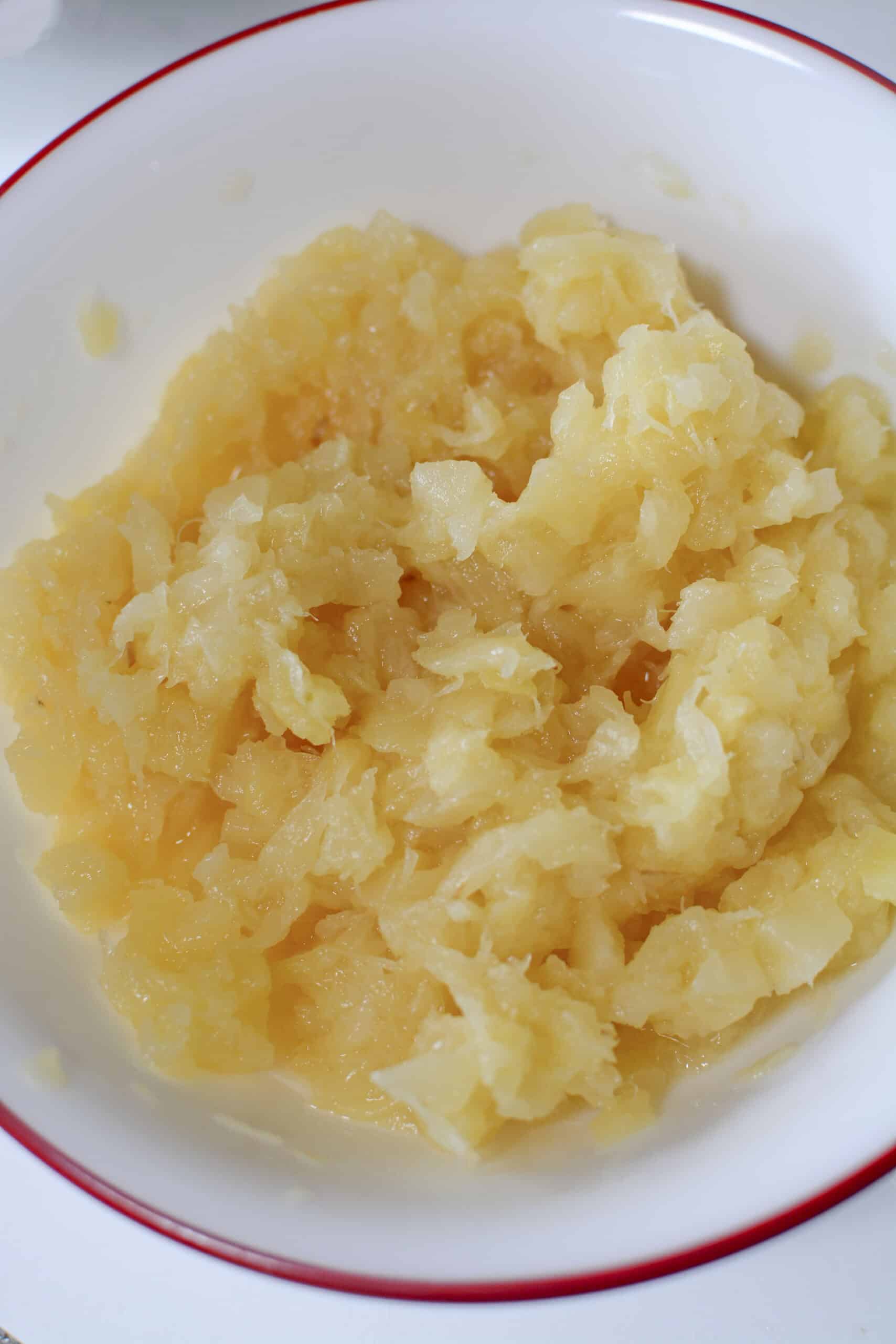 Drained pineapple in a white bowl with a red rim.