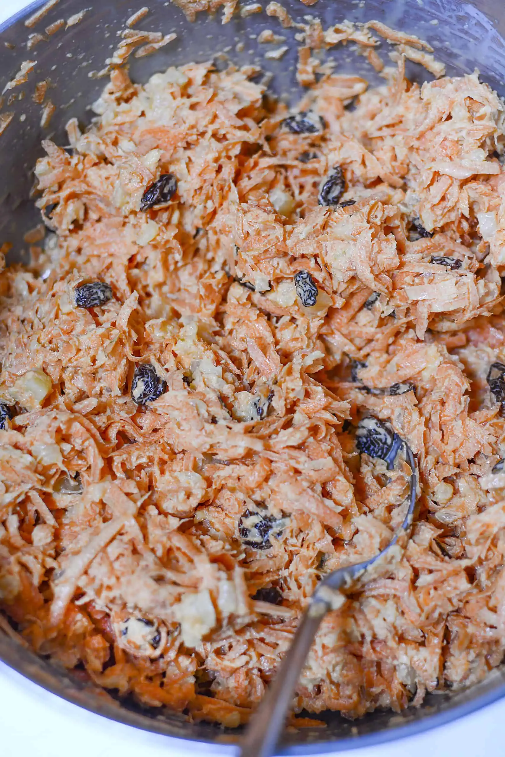 Carrot salad all mixed together in a silver bowl.