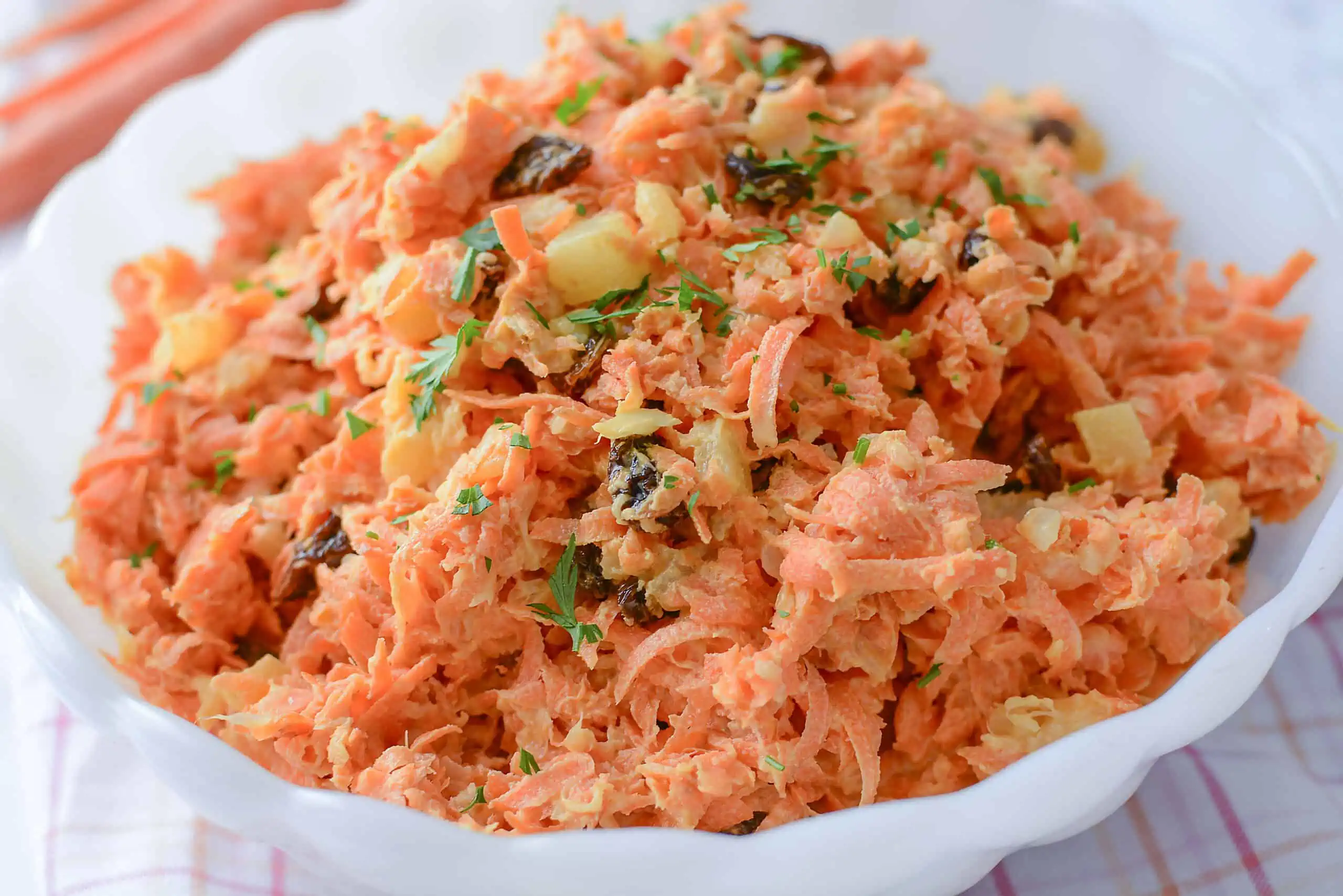 Shredded carrot pineapple salad in a white bowl.