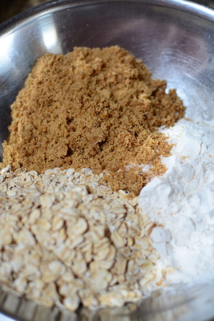 The ingredients for the topping are in a silver bowl. Brown sugar, flour, oats.