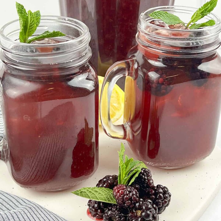 Two cups of iced tea with fresh blackberries in the foreground.