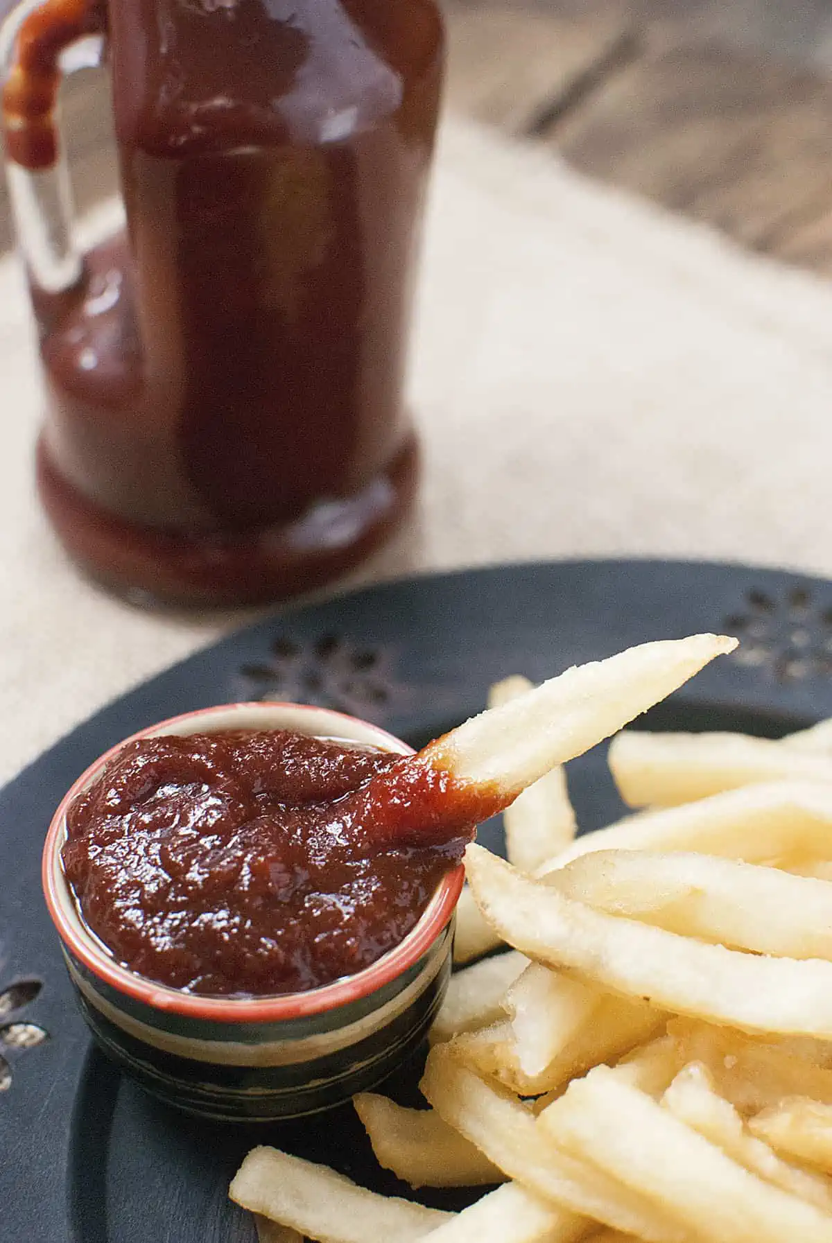 A french fry sticking out of a small bowl of ketchup.