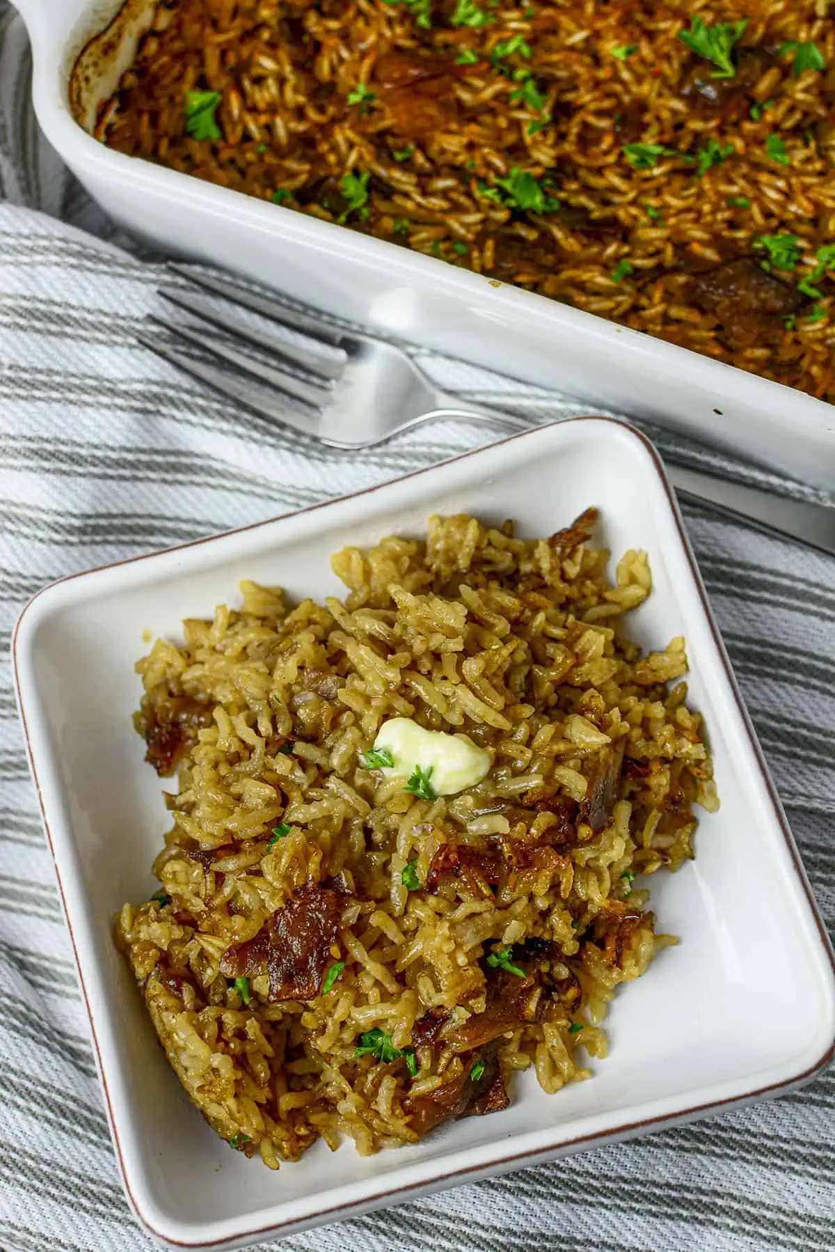 A plated amount of the french onion rice with a pat of butter on top.