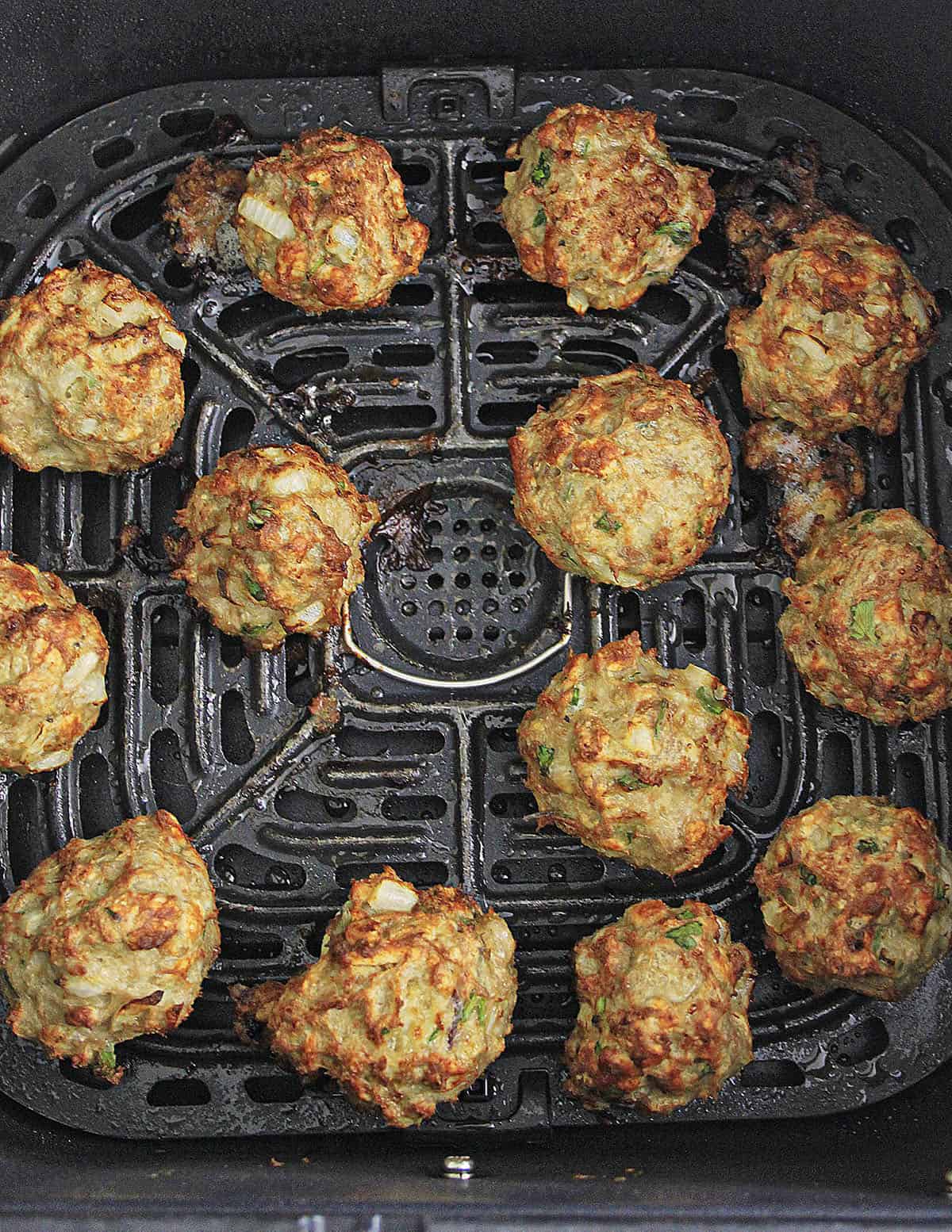 Twelve chicken meatballs in the basket of the air fryer.