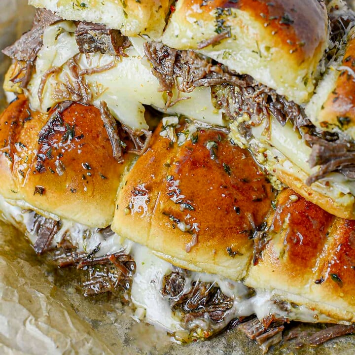 Two rows of beef brisket sliders on parchment paper.