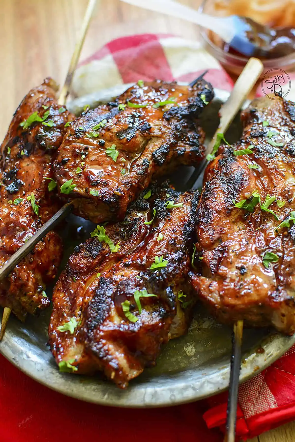 Grilled boneless country style ribs sit in a tin plate, ready to be eaten.