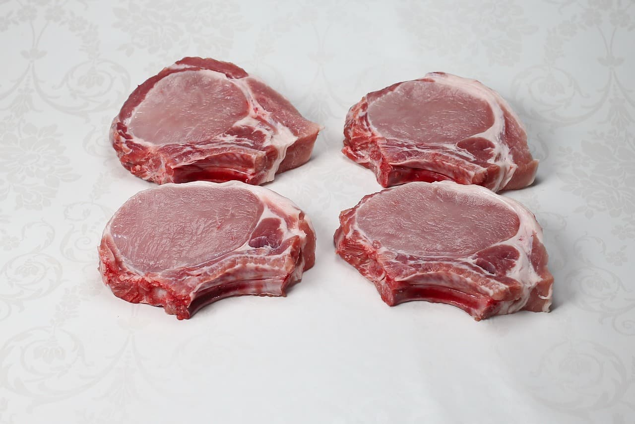 4 pork chops on a white table.