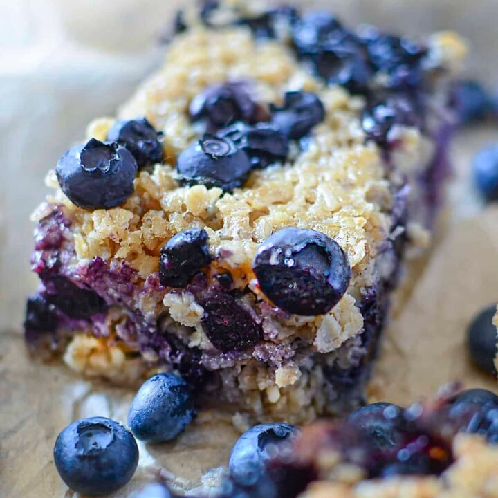 One blueberry oat square with fresh blueberries around it.