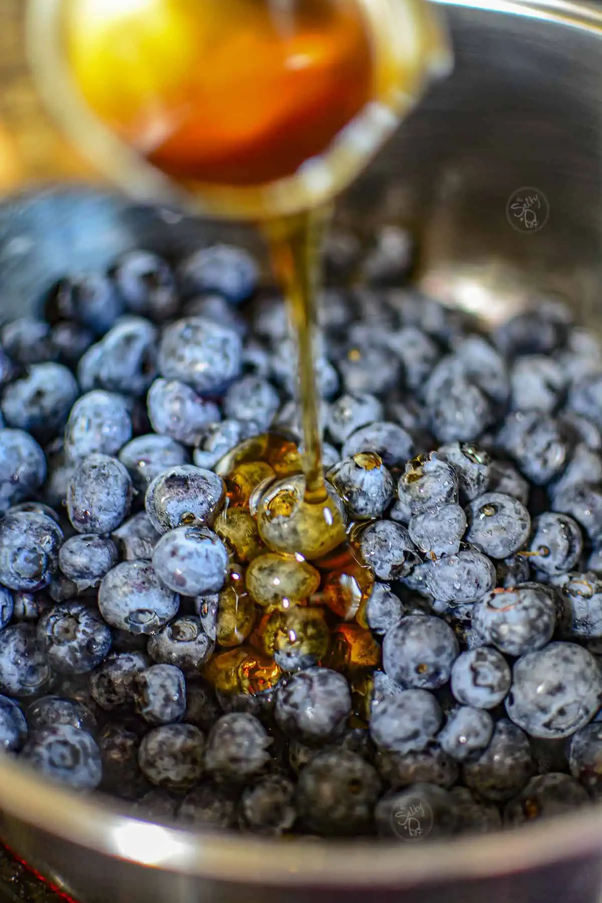 Pouring honey into the blueberries.