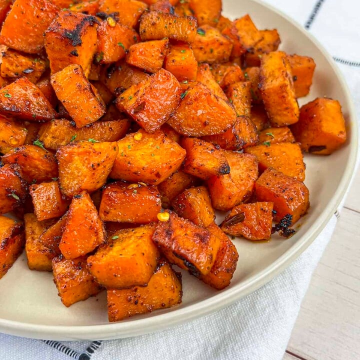 Roasted sweet potatoes on a cream colored plate.