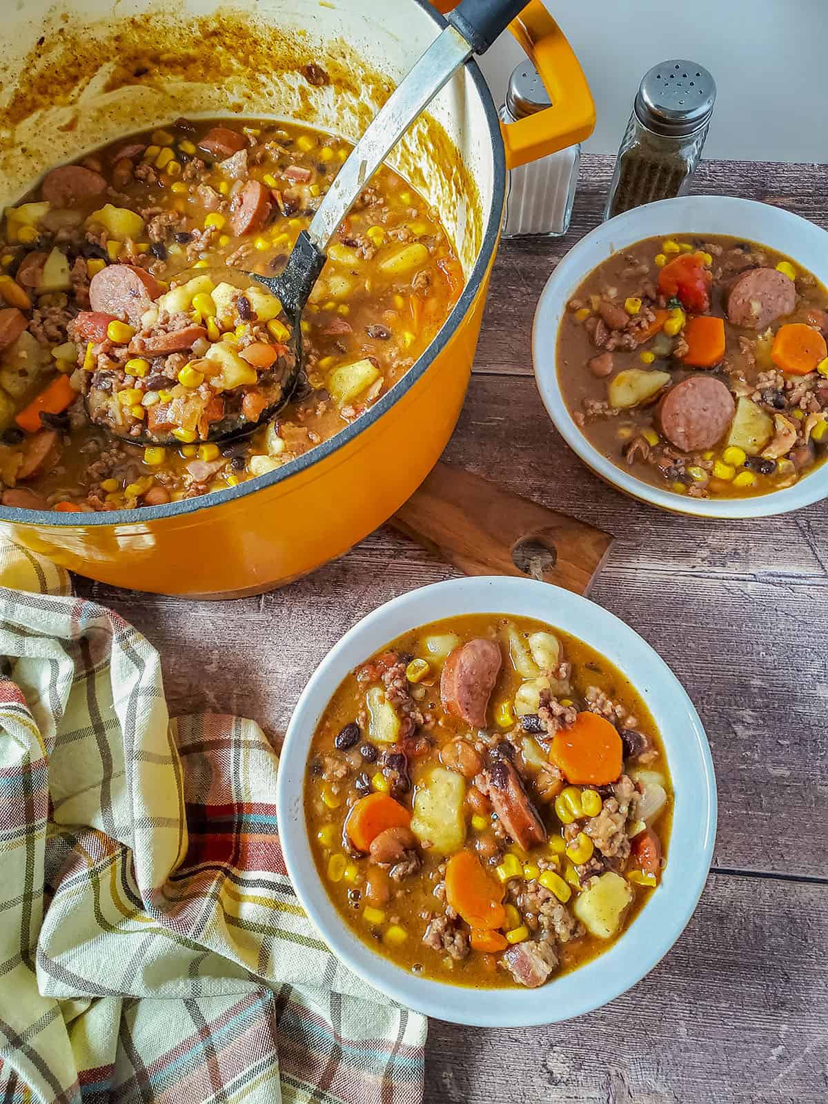 Cowboy soup in a dutch oven with bowls on the side, filled with soup as well. 