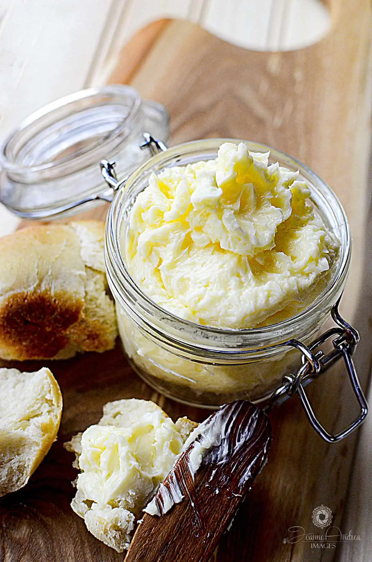 Fresh butter in a jar on a wooden cutting board.