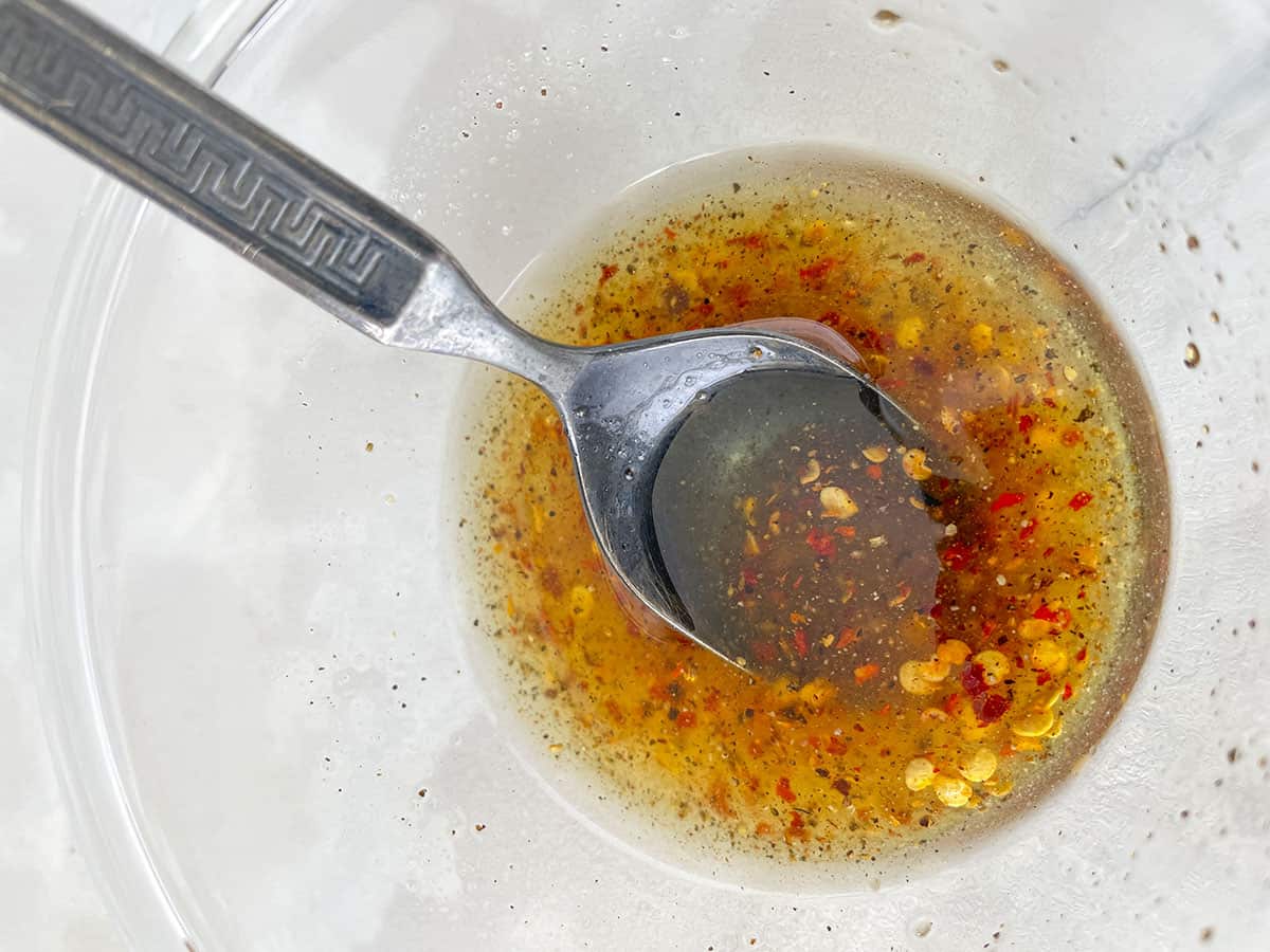 Hot honey mixed with salt and pepper in a bowl with a spoon in it. 