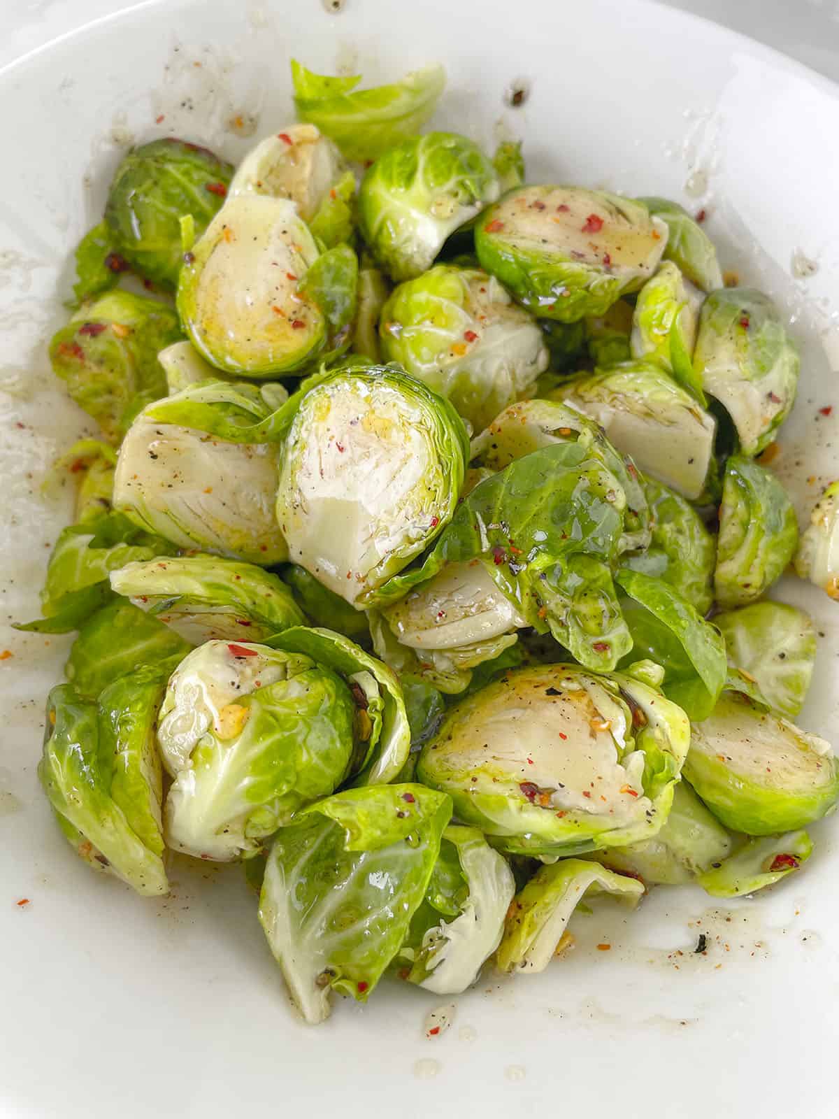 The hot honey added to the sprouts in a white bowl. 