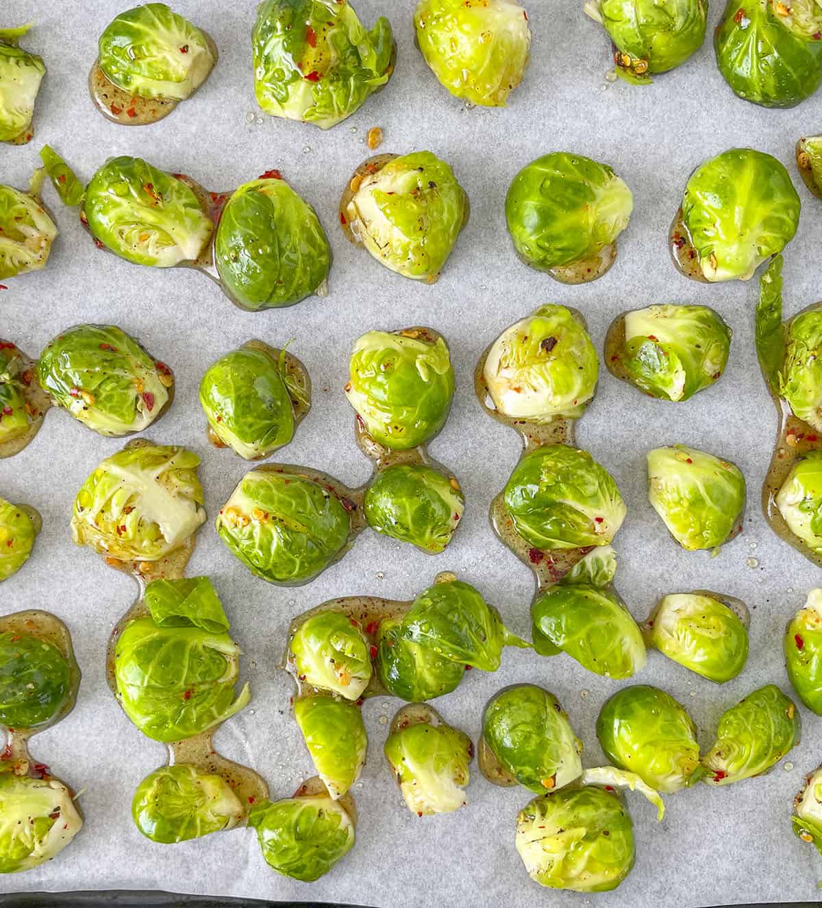 The seasoned brussels sprouts placed on a parchment lined baking sheet, cut side down. 