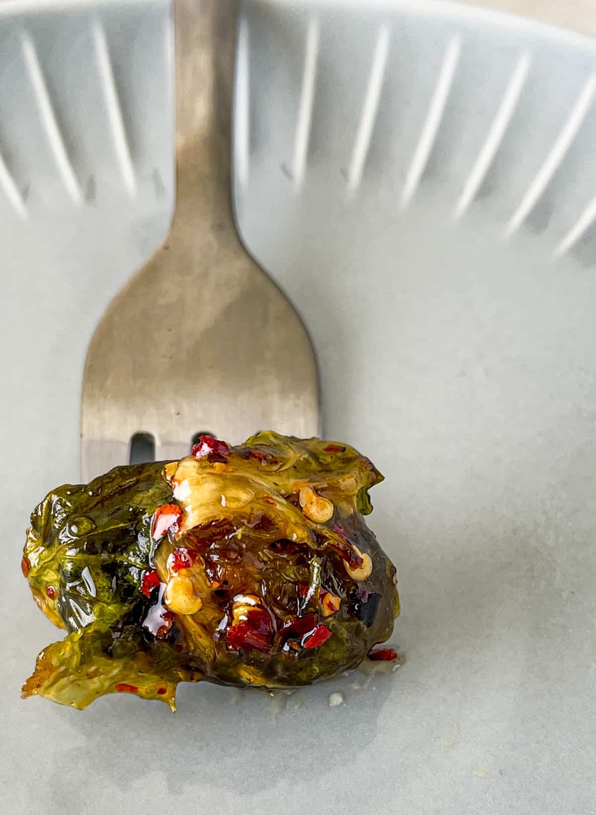 A fork with one roasted brussels sprout on it.