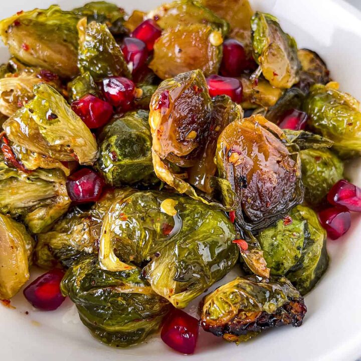 Roasted Hot Honey Brussels Sprouts with Pomegranate in a white bowl.