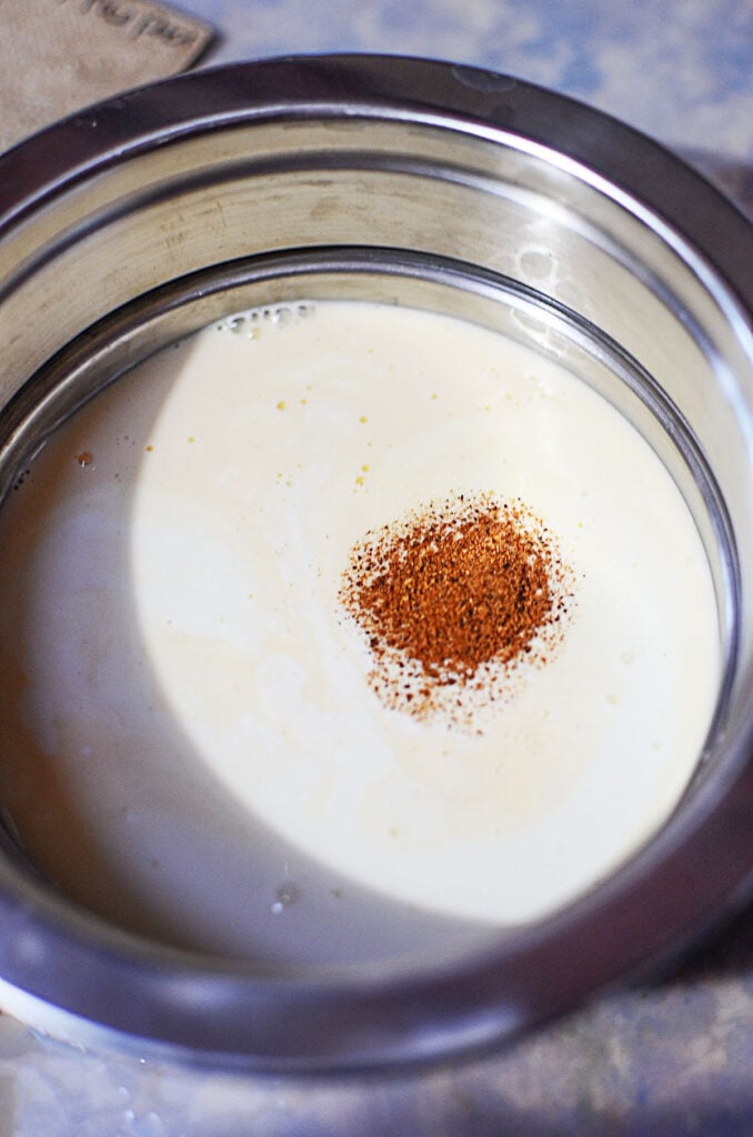 The egg mixture in a silver bowl with nutmeg on top. 