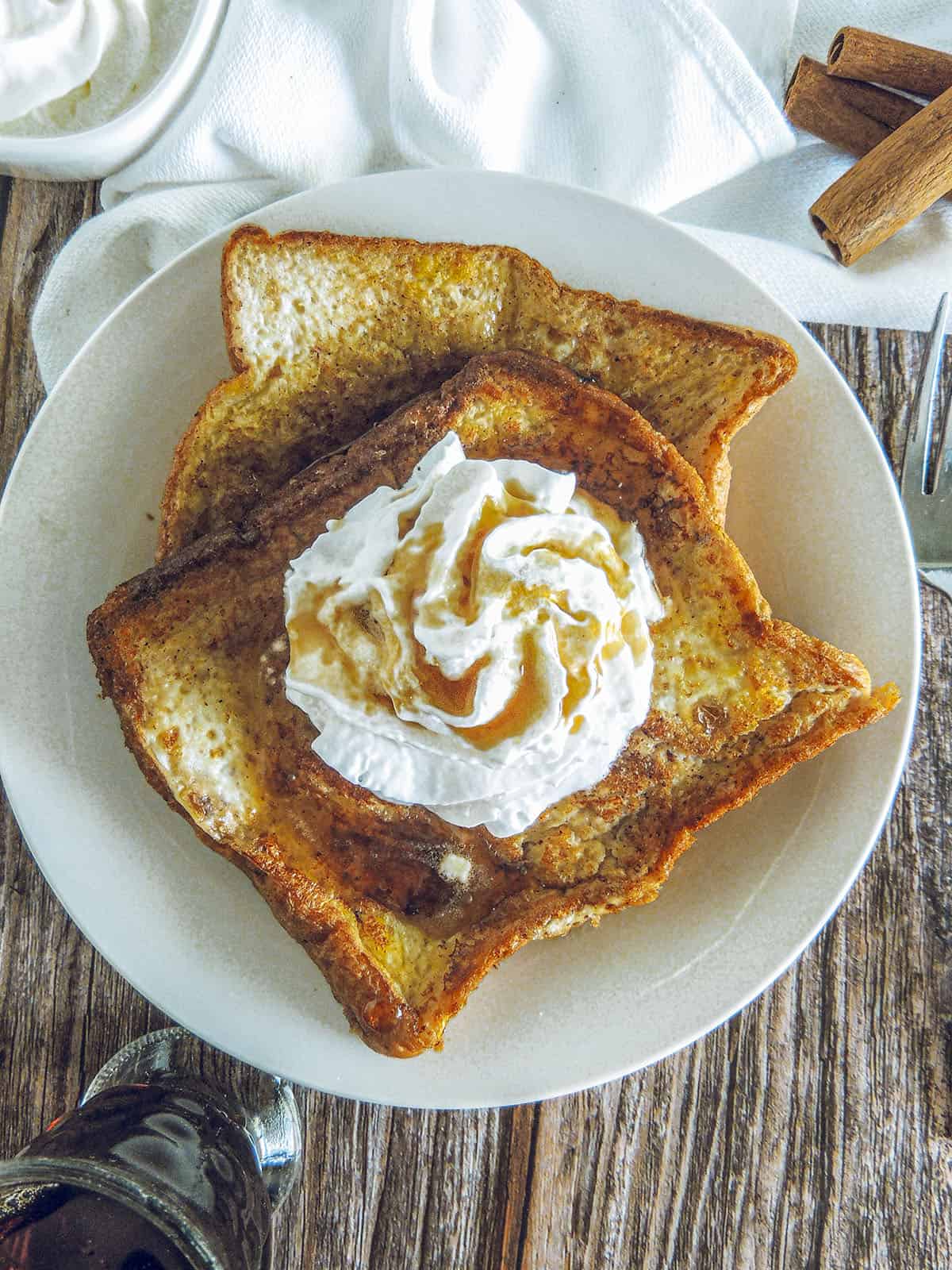 Two pieces of baileys french toast on a cream colored plate.