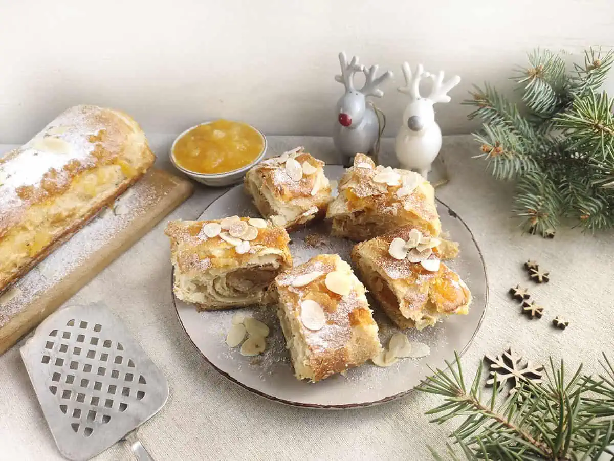 Dutch almond paste pastry arranged on a plate with rudolph decorations and other christmas themed items around the plate on the table.