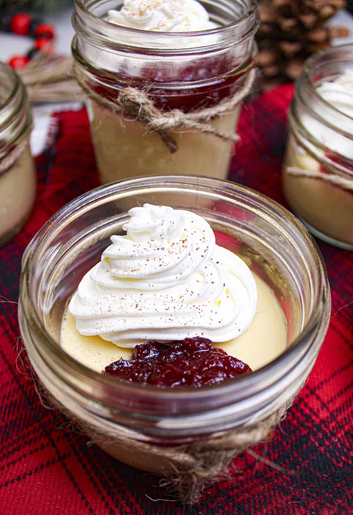 One Christmas panna cotta dessert with whipped cream and sweet cranberry sauce on top.