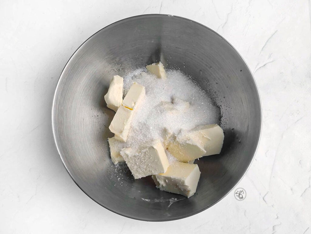 Butter and sugar sit in a metal bowl.